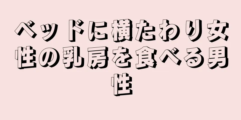 ベッドに横たわり女性の乳房を食べる男性